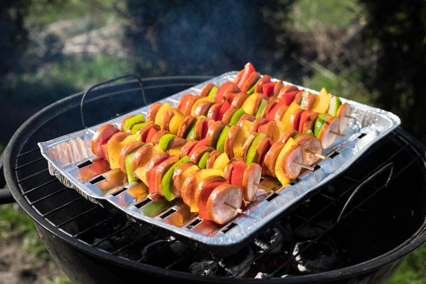 brochetas coloridas de salchicha a la parrilla en un día soleado, el concepto de asar a la parrilla foto