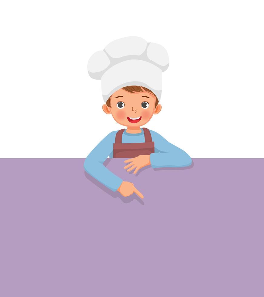 cute little boy in chef hat and apron standing behind empty board pointing finger to blank banner for copy space vector