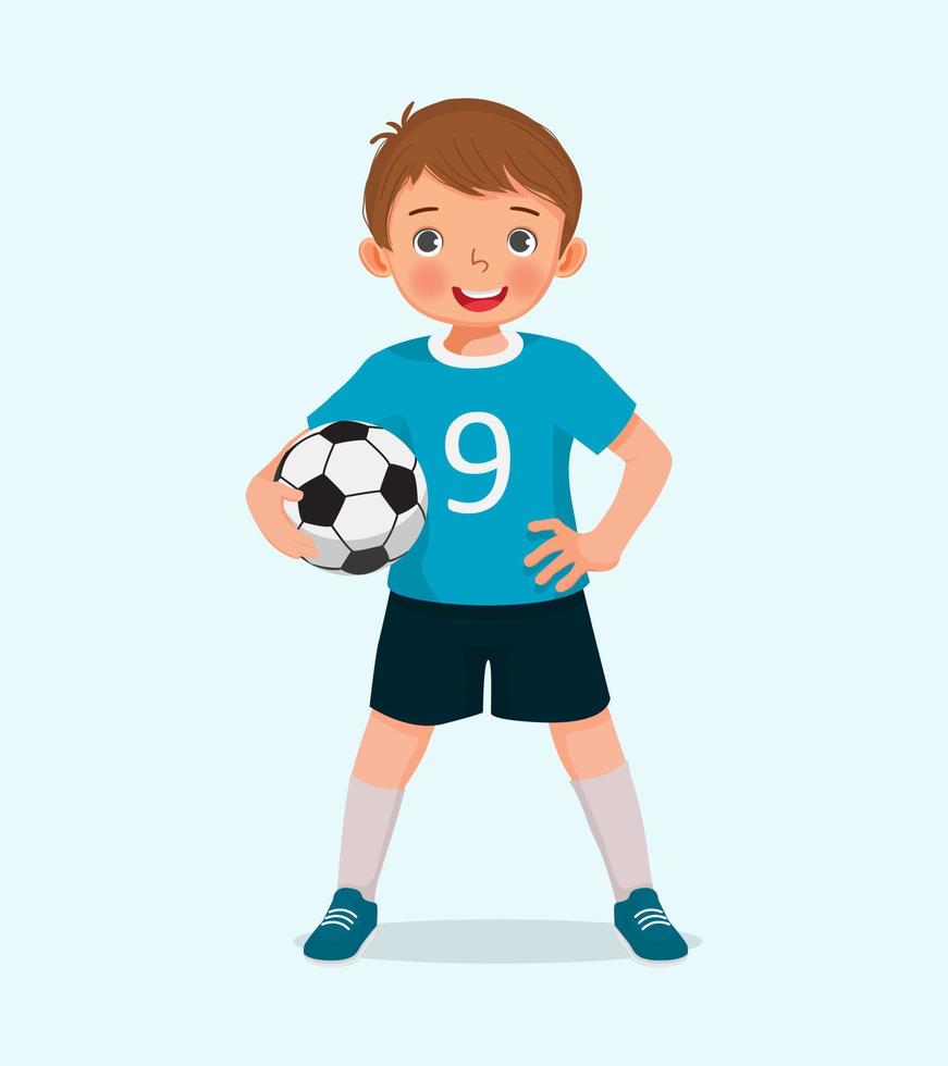 Portrait of cute little boy in sportswear holding a soccer ball posing with hand on the waist vector