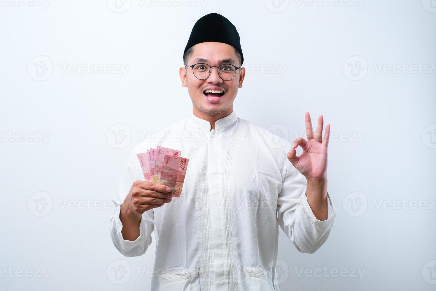 musulmán asiático sonriendo feliz mientras sostiene papel moneda foto