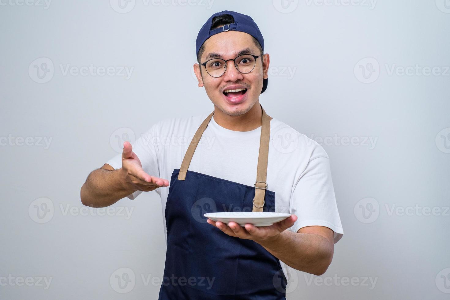 Asian barista man showing excited expression while holding empty dinner plate photo