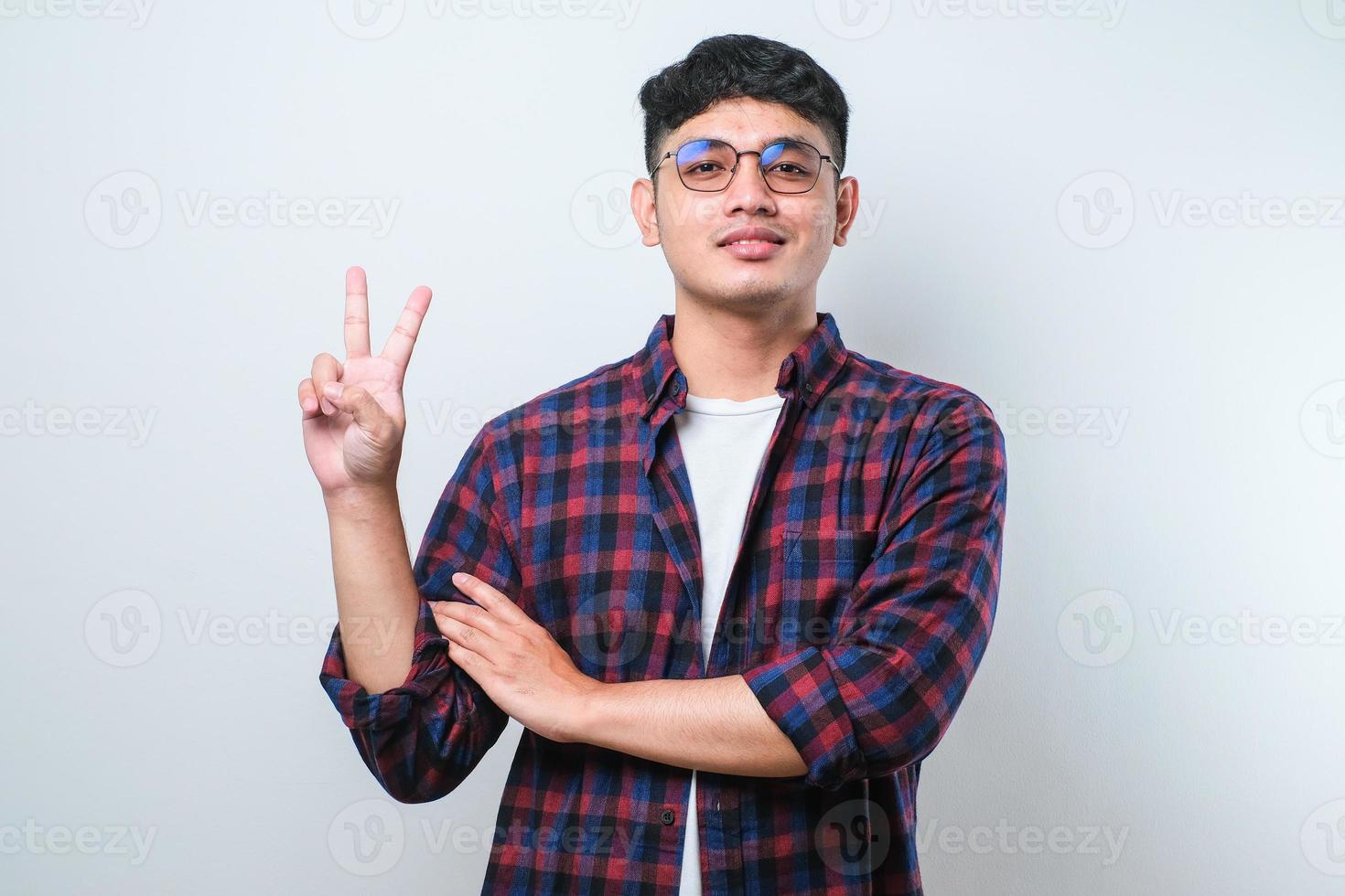 Young handsome asian guy doing peace symbol with fingers over face, smiling cheerful showing victory photo