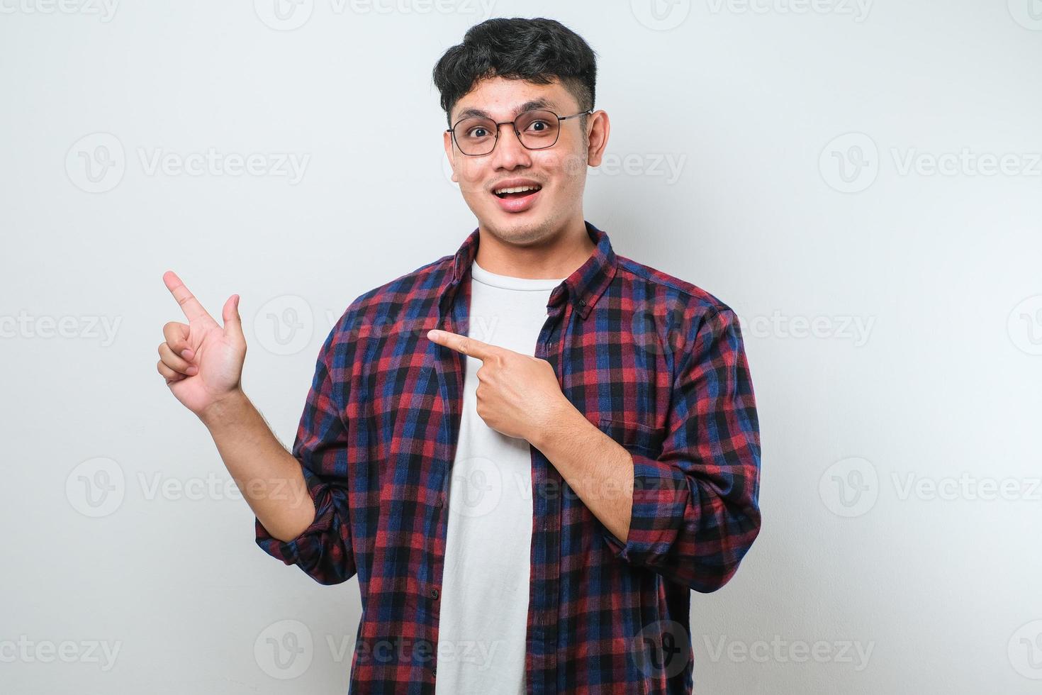 Young handsome asian man pointing with hand finger to the side looking at the camera. photo