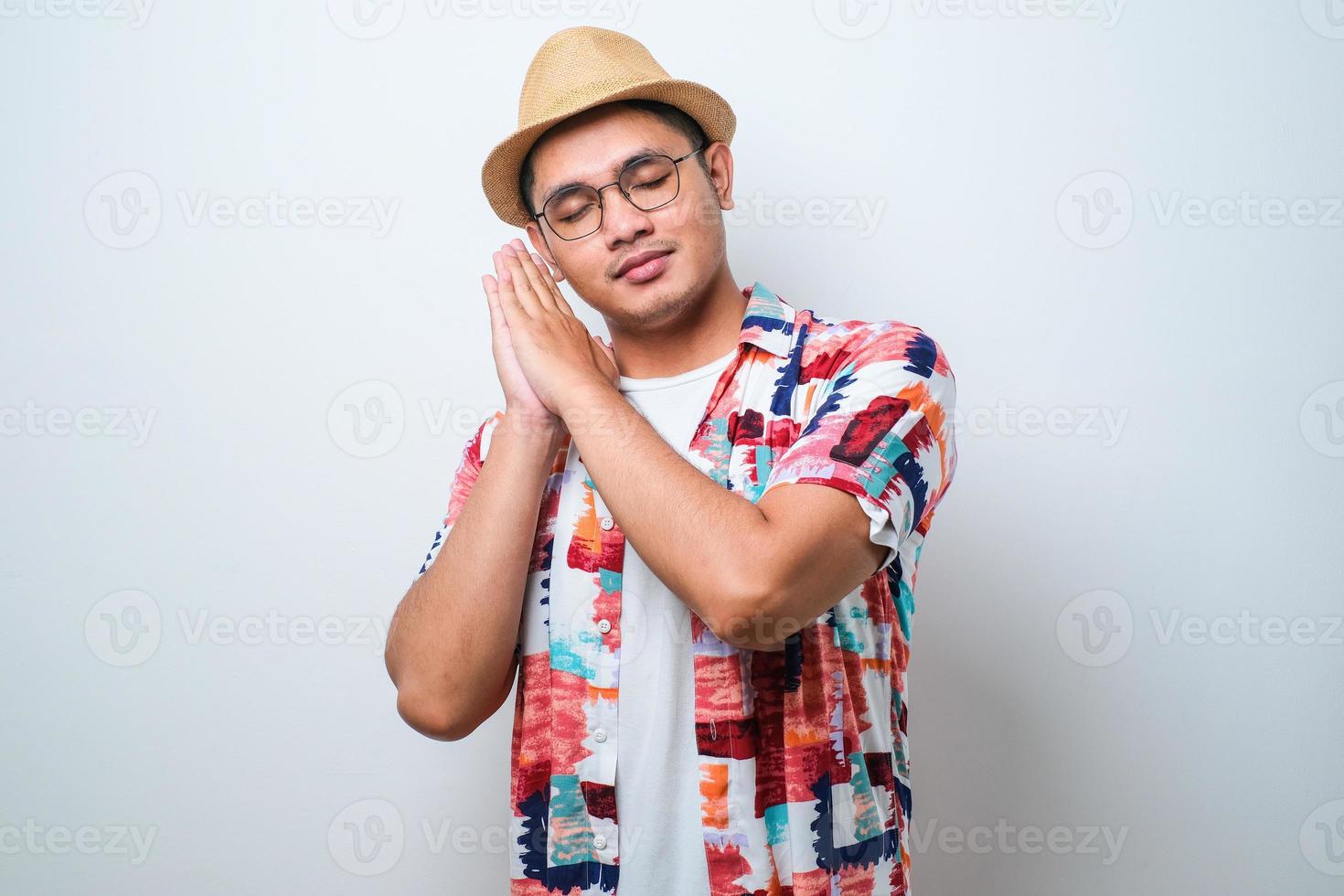 Young handsome Asian man wearing casual beach shirt sleeping tired dreaming and posing with hands together while smiling with closed eyes photo