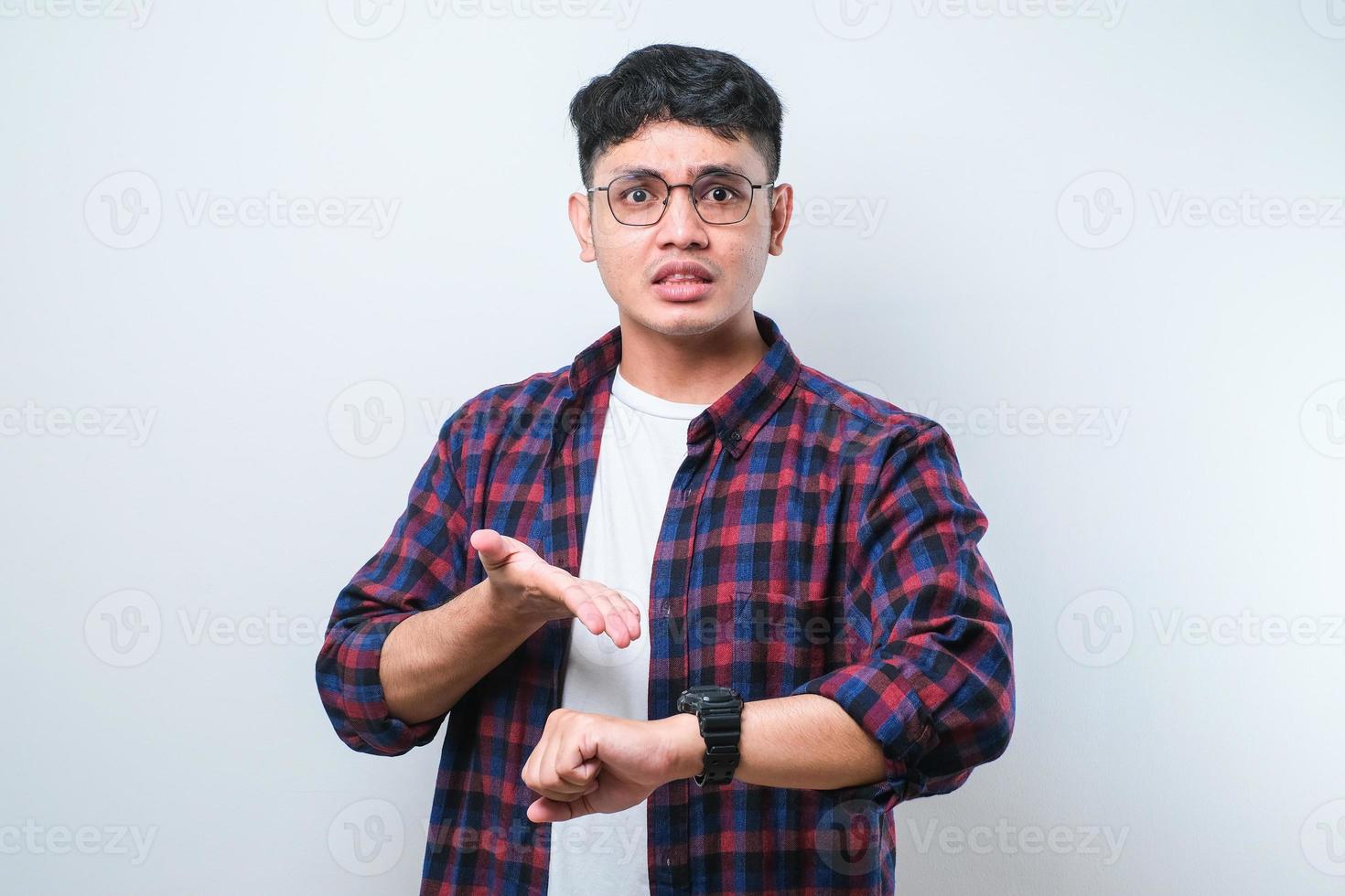 Young handsome man in hurry pointing to watch time, impatience, upset and angry for deadline delay photo