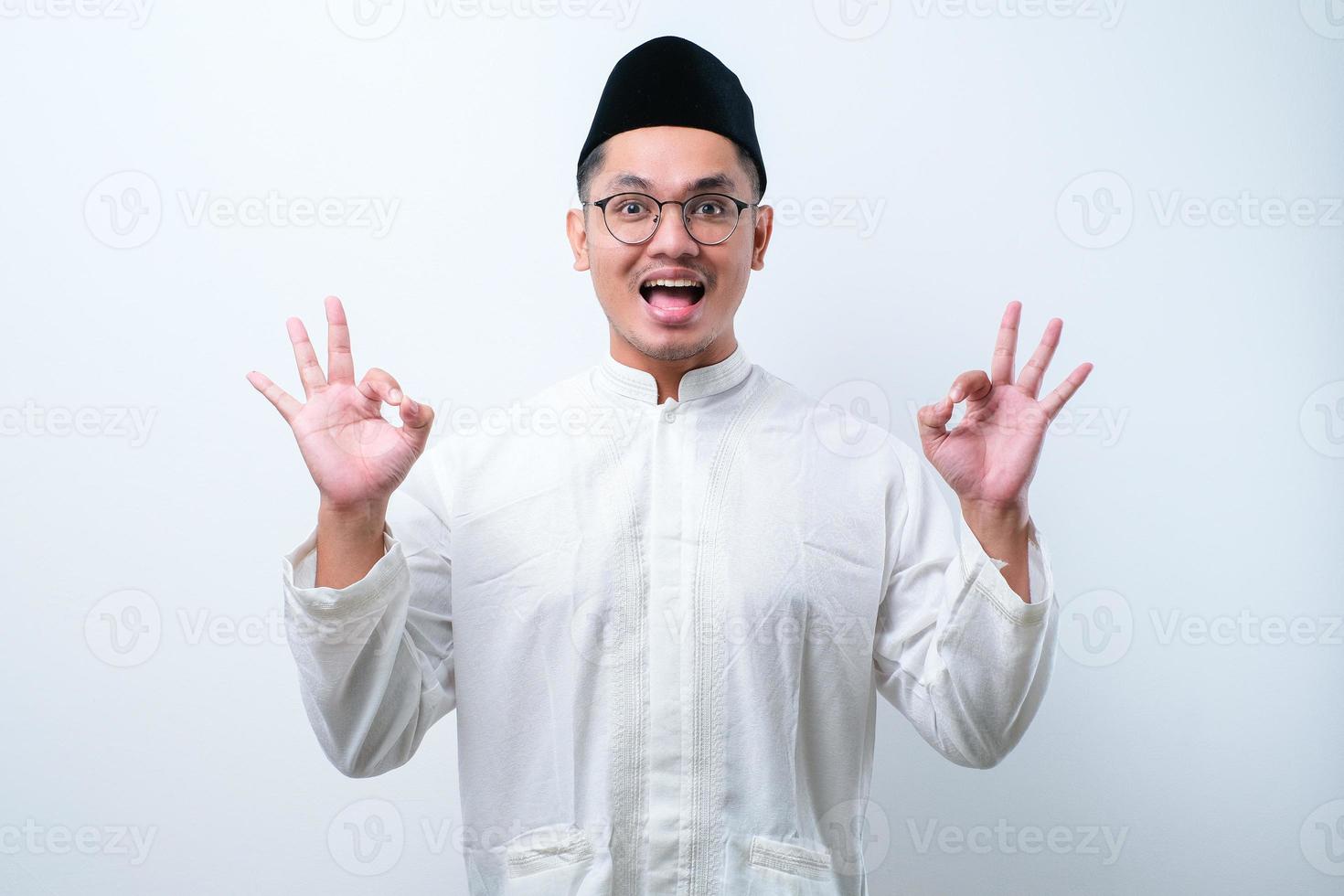 Asian muslim man approving doing positive gesture with hand, thumbs up smiling and happy for success. Winner gesture. photo