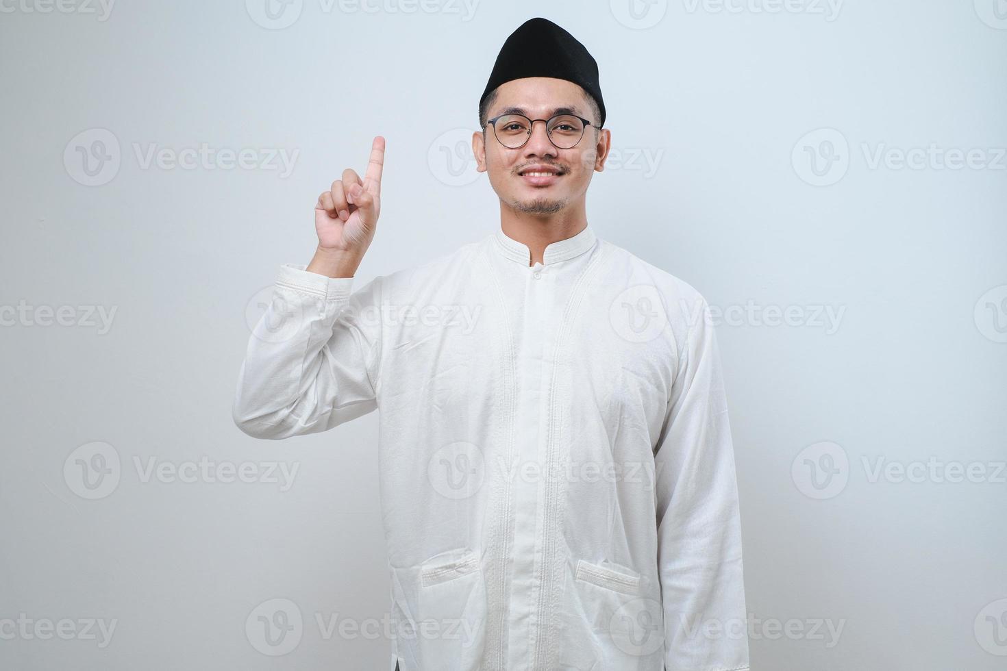 Asian muslim man wearing casual clothes showing and pointing up with fingers number one while smiling confident and happy photo