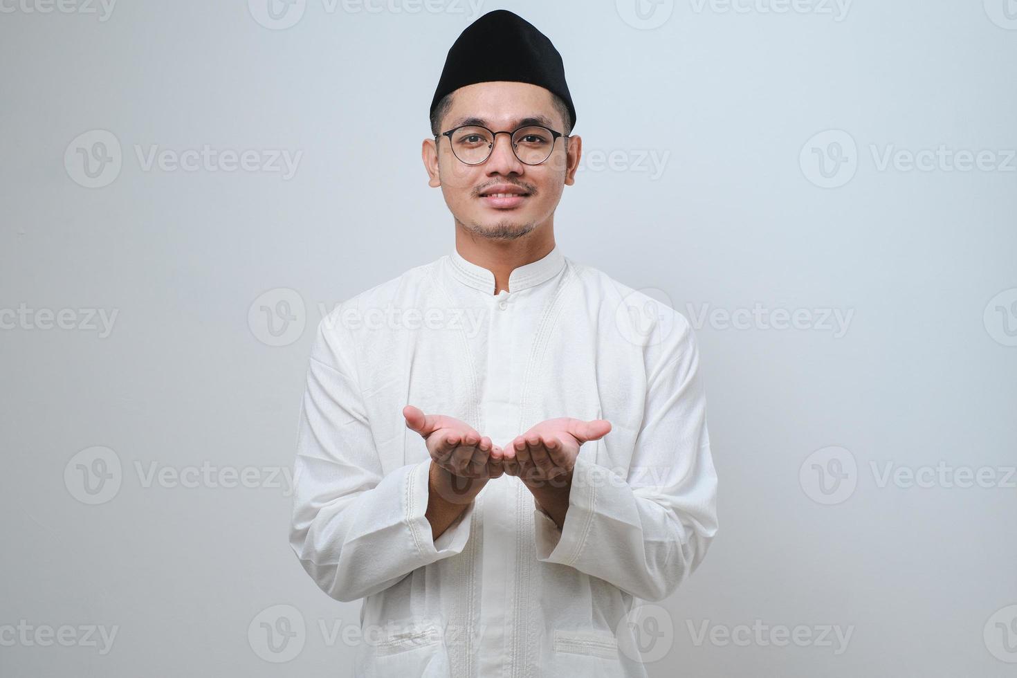 Asian muslim man showing his empty palm to the front, holding sometihing photo