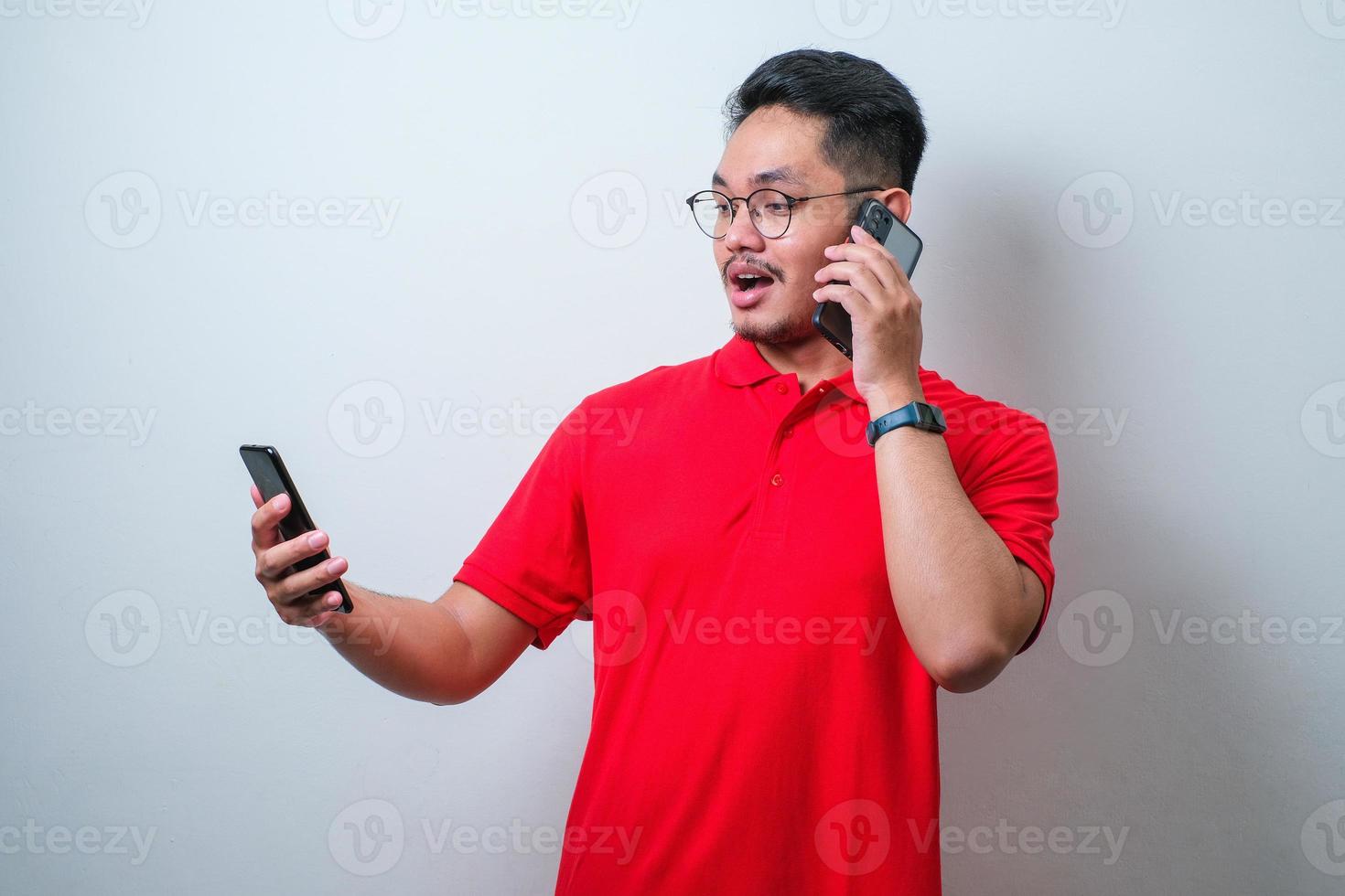 Young asian man showing shocked face when caling someone and sending message to other photo