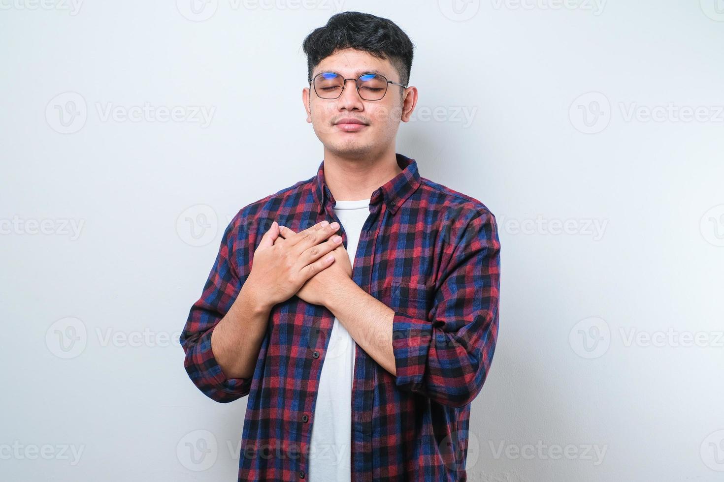 Handsome young man smiling with hands on chest with closed eyes and grateful gesture on face over white background. health concept. photo