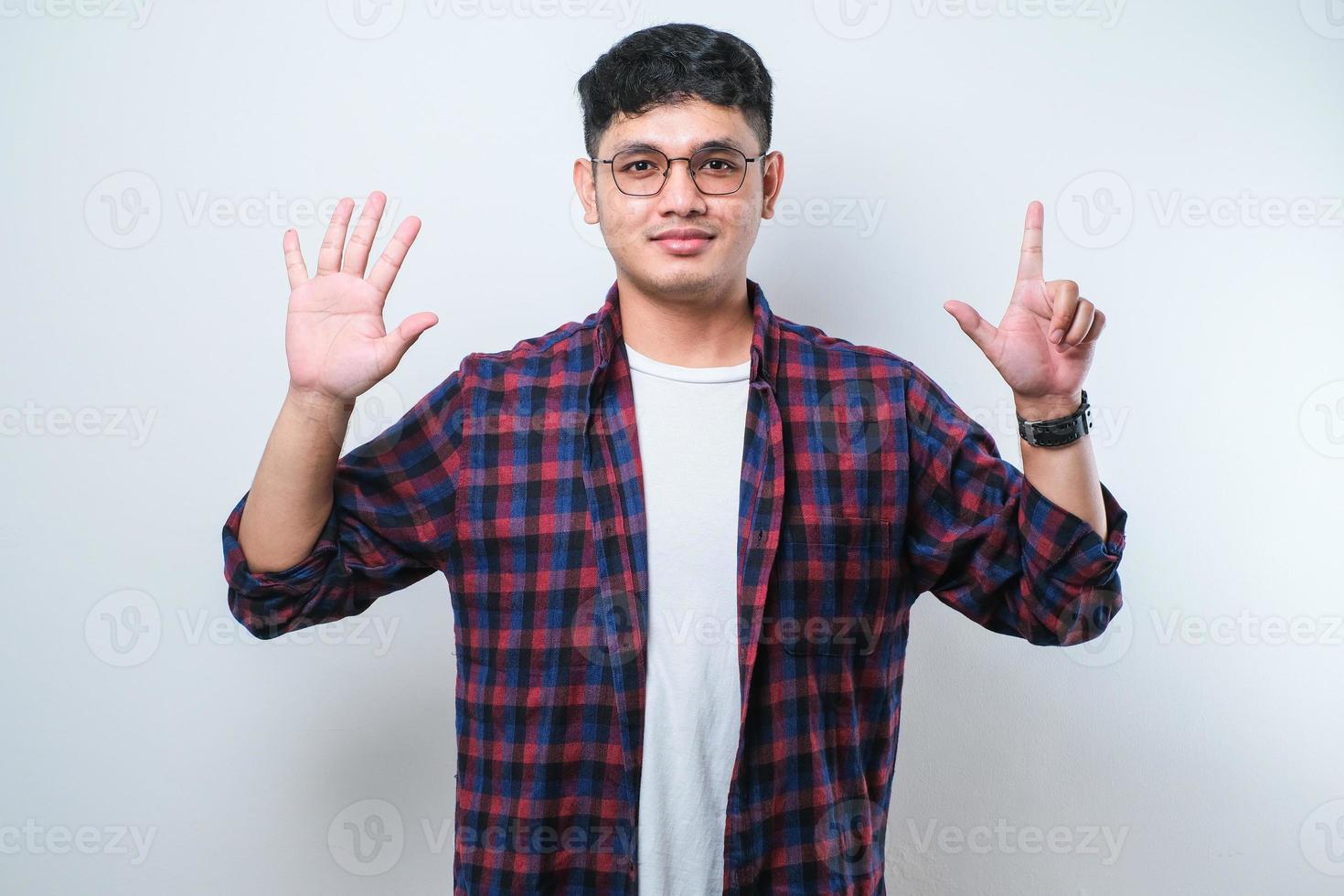 Young handsome Asian man wearing casual clothes showing and pointing up with fingers number seven while smiling confident and happy photo