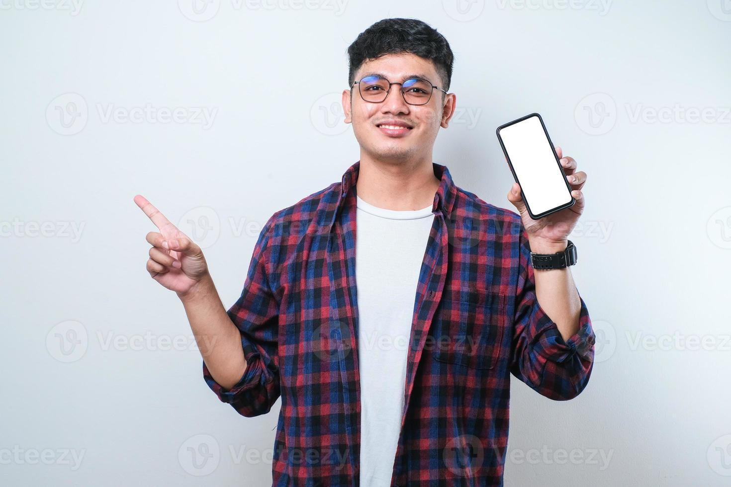 Young handsome asian man showing blank screen of smartphone very happy pointing with hand and finger to the side photo