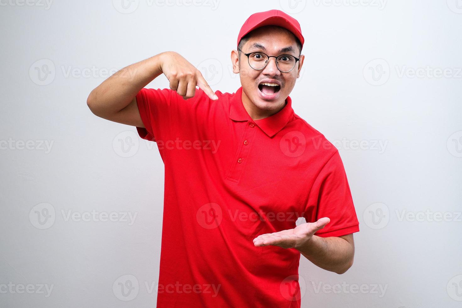 Asian courier man wearing red uniform and cap pointing something on his empty palm with exited expression photo
