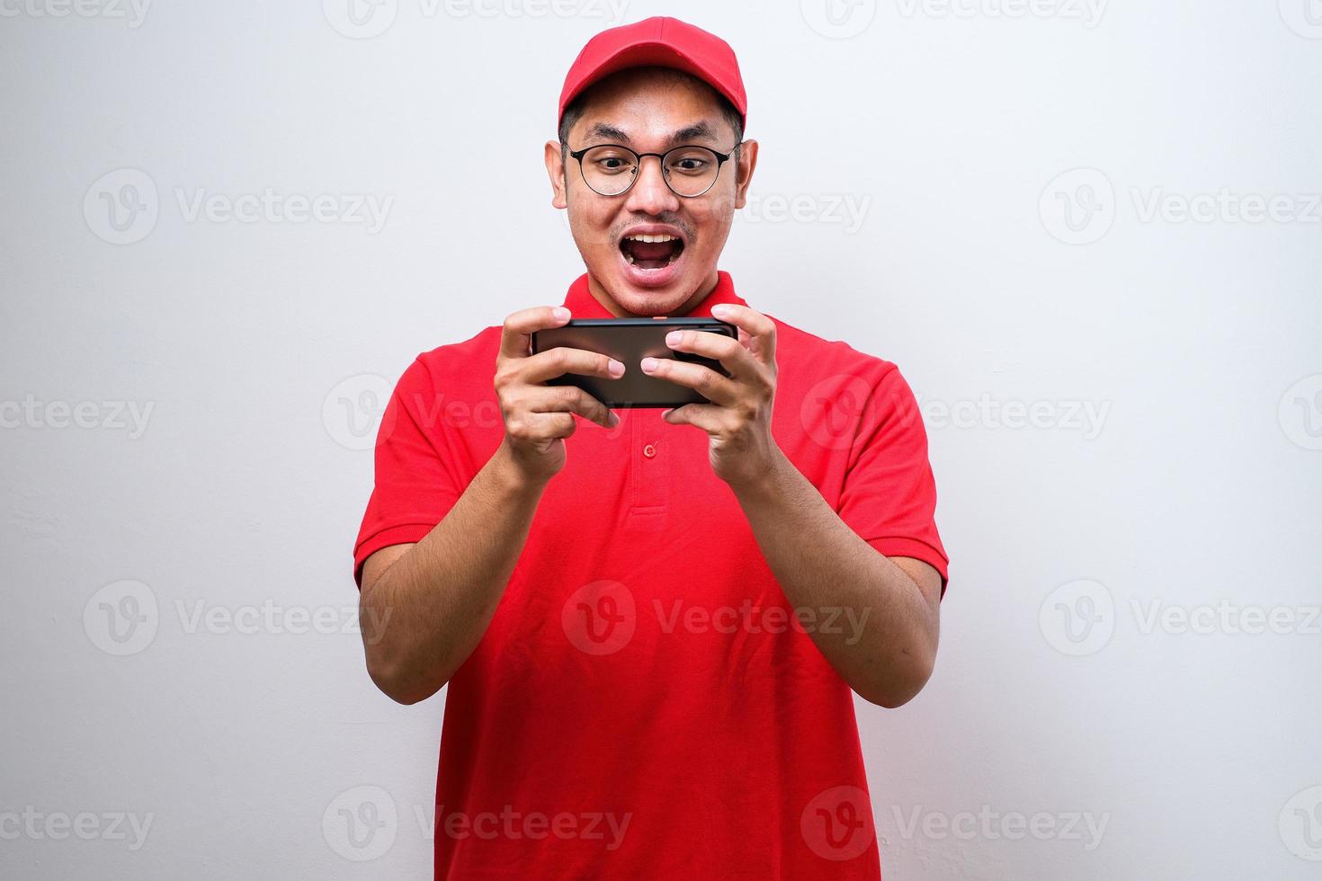 Shocked asian delivery man wearing glasses holding and pointing on phone cellular photo