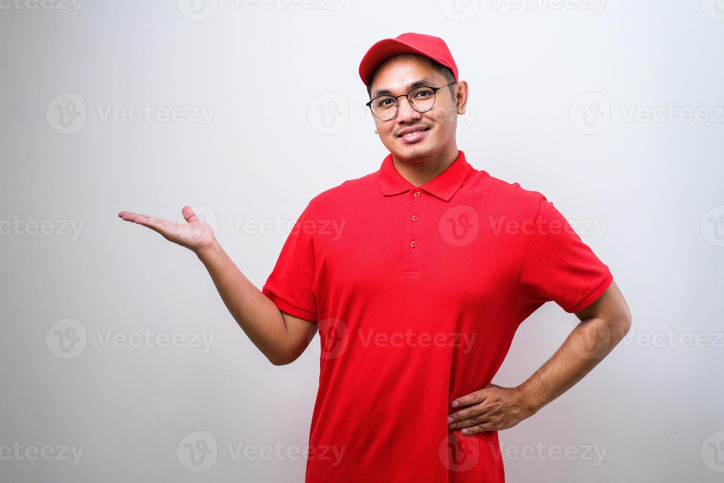 un joven y apuesto repartidor chino señalando con la mano y el dedo a un lado mirando la cámara. foto