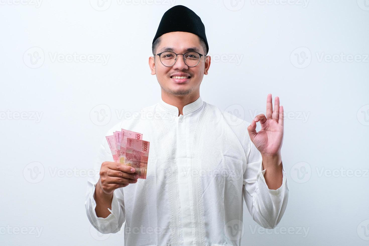 musulmán asiático sonriendo feliz mientras sostiene papel moneda foto