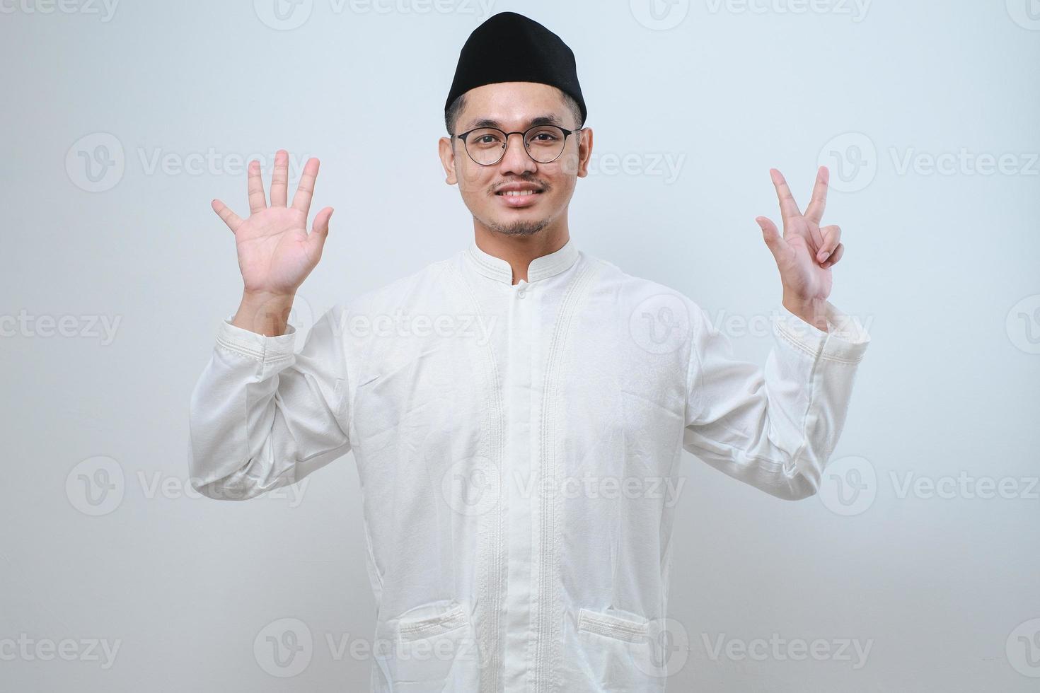 Asian muslim man wearing casual clothes showing and pointing up with fingers number eight while smiling confident and happy photo