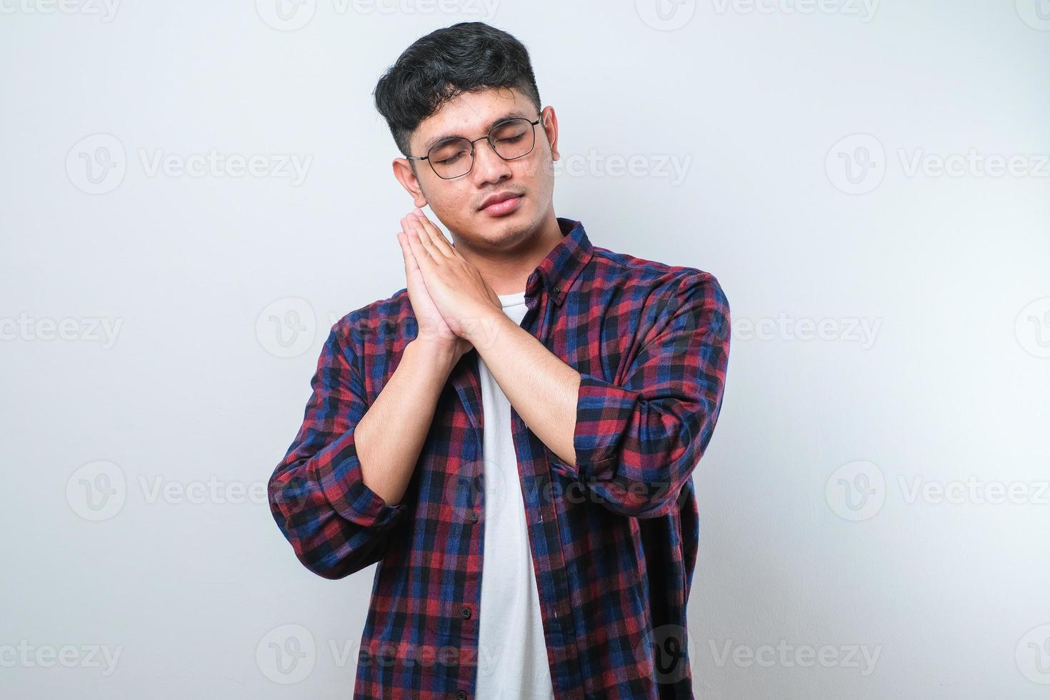 Asian handsome man wearing shirt sleeping tired dreaming and posing with hands together while smiling with closed eyes photo
