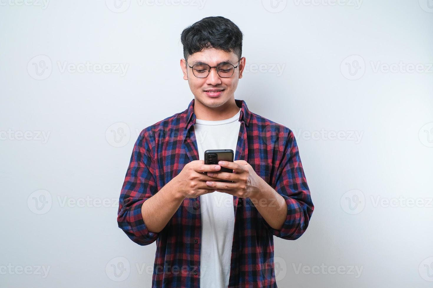 Smiling young good looking Asian man using smartphone to get in touch with family and friends photo