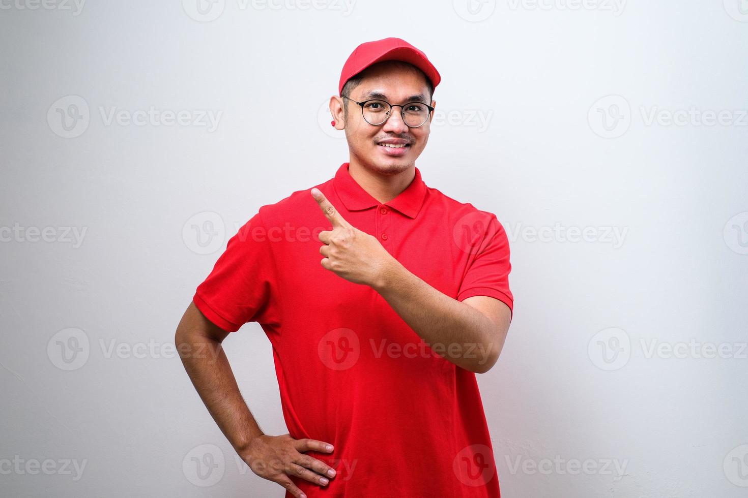 un joven y apuesto repartidor chino señalando con la mano y el dedo a un lado mirando la cámara. foto