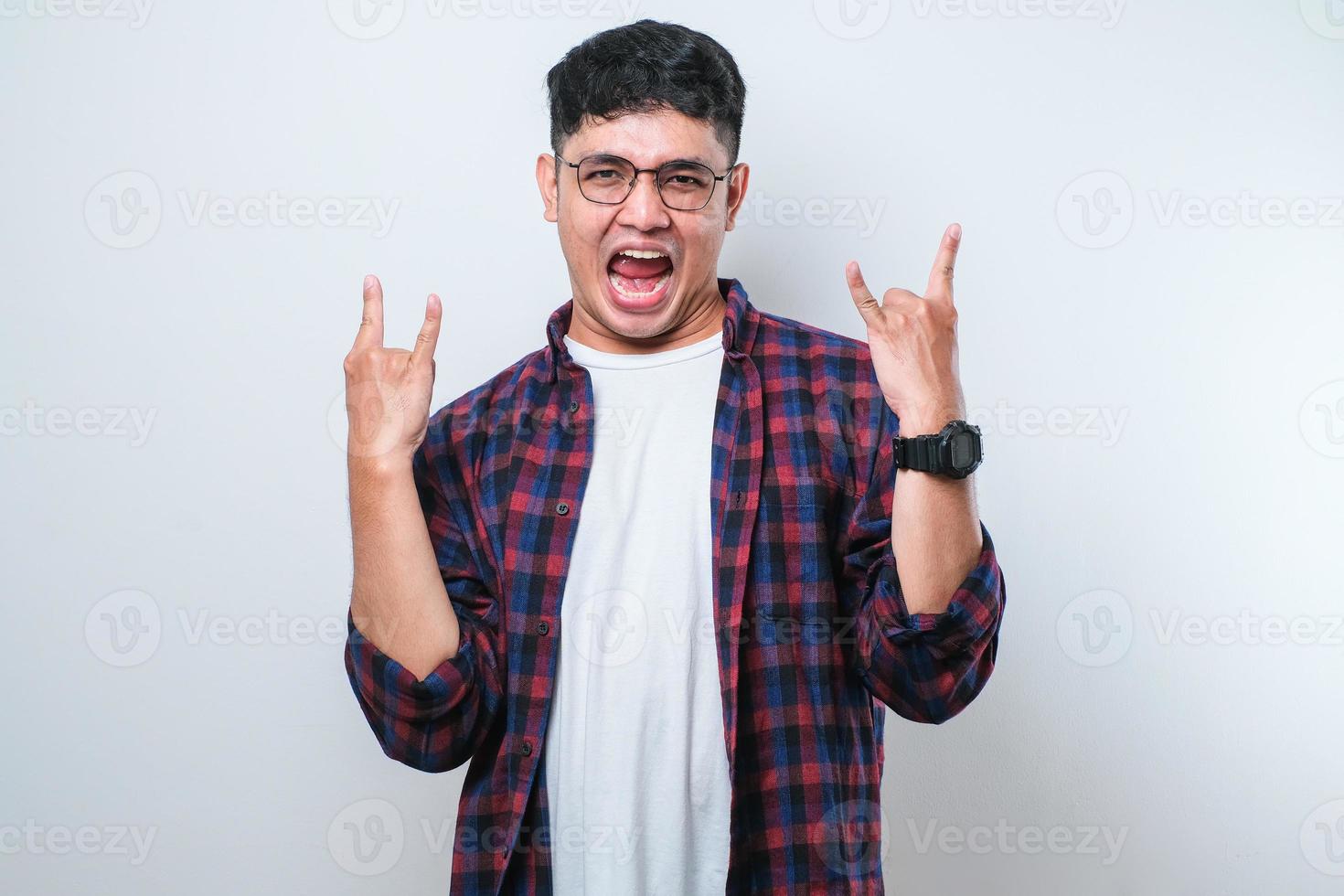 Handsome man with shouting with crazy expression doing rock symbol with hands up. Music star. Heavy concept. photo