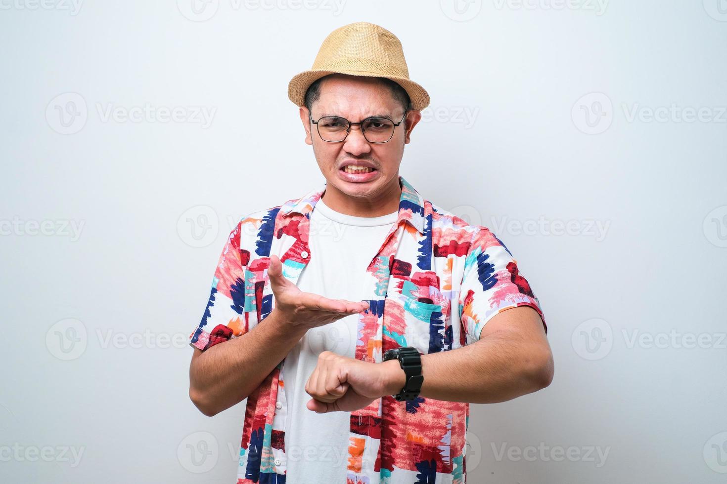 hombre asiático con camisa de playa casual mirando la hora del reloj preocupado, temeroso de llegar tarde foto