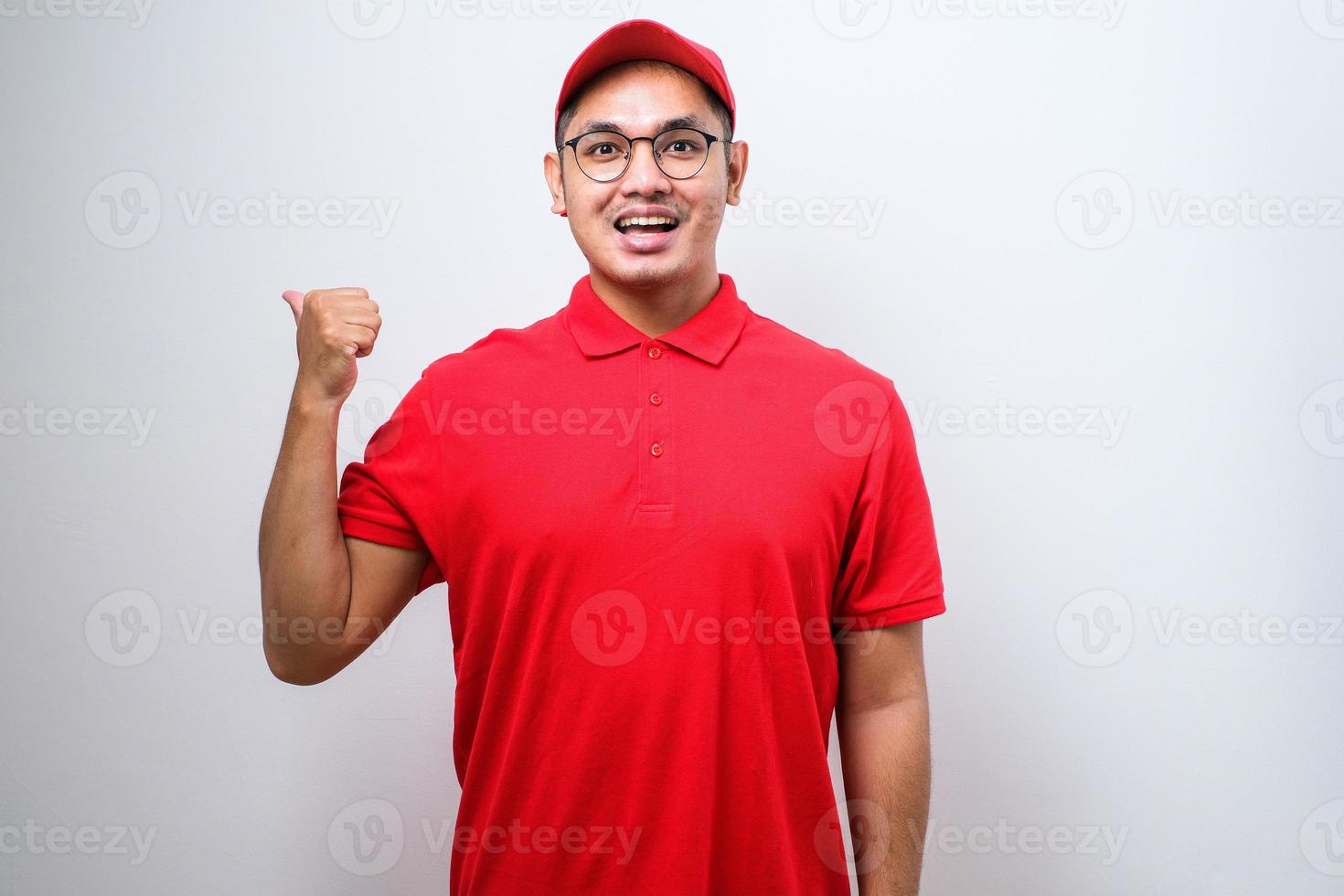 Delivery man with a big smile on face, pointing with hand and finger to the side looking at the camera. photo
