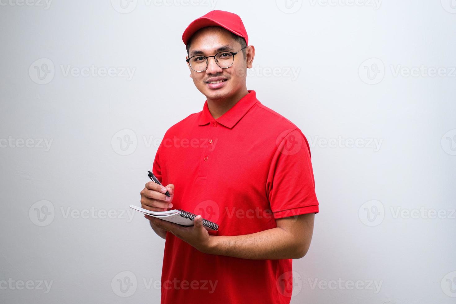 joven y apuesto repartidor asiático sonriente tomando el pedido con mente de servicio foto