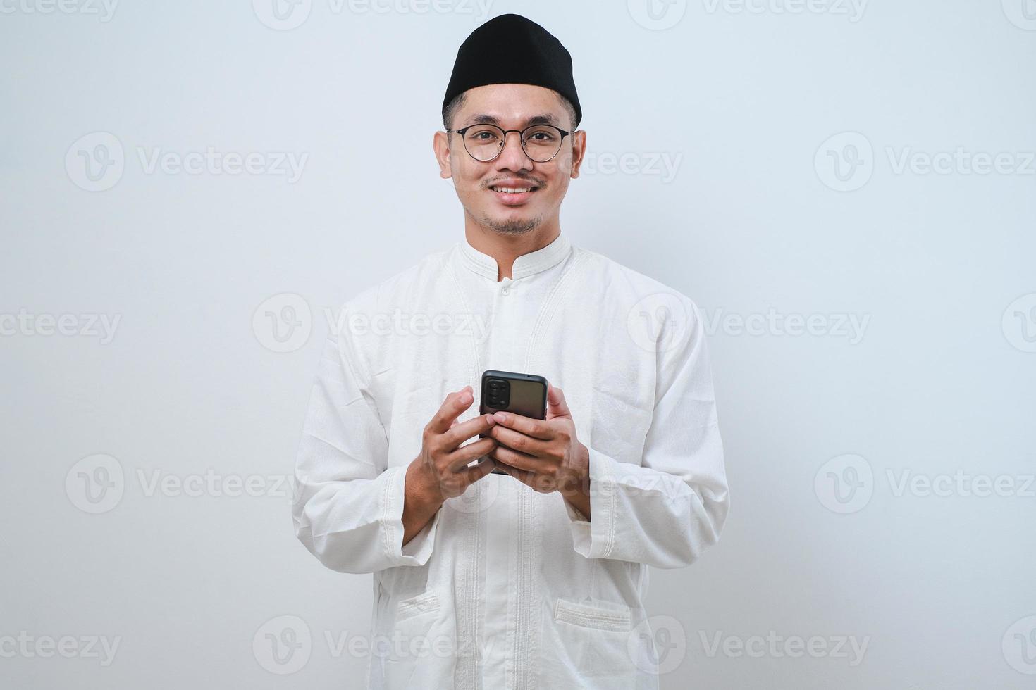 Happy asian muslim man holding and pointing on phone cellular photo