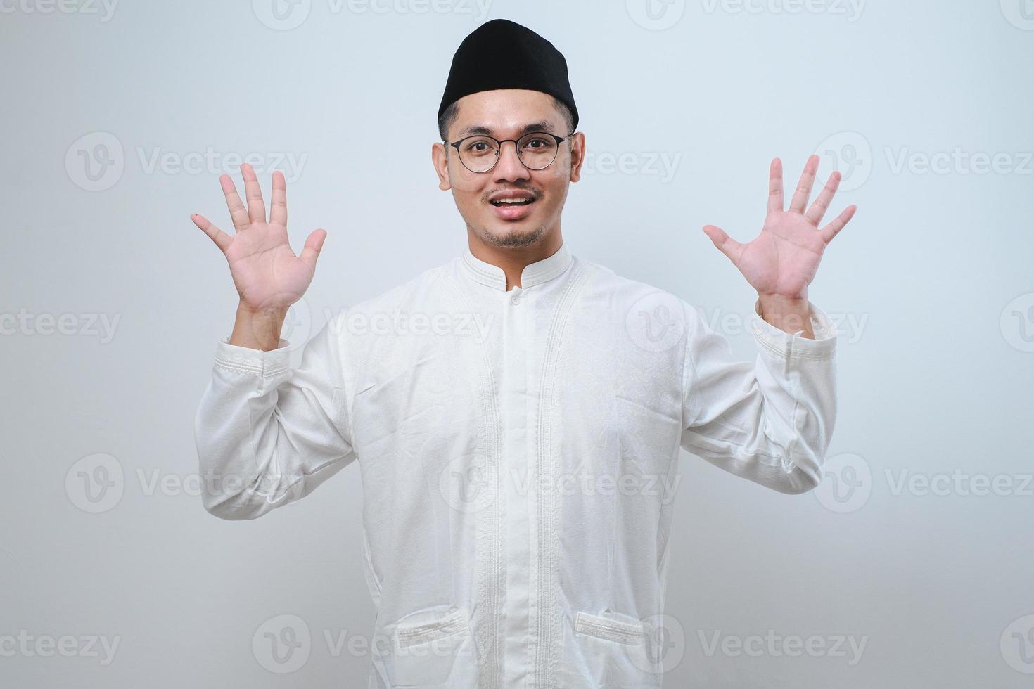 Asian muslim man wearing casual clothes showing and pointing up with fingers number ten while smiling confident and happy photo