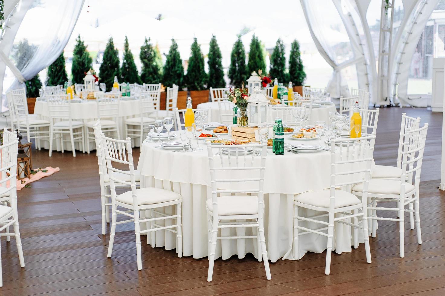 mesas redondas cubiertas con tela azul en un pabellón de bodas blanco foto