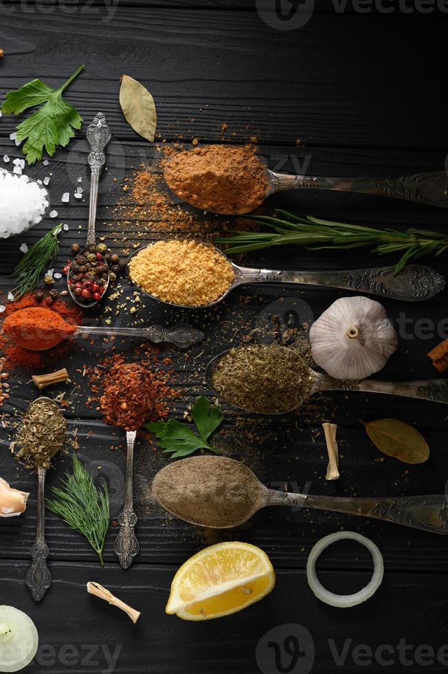 Colorful various herbs and spices for cooking on dark wooden rustic background photo