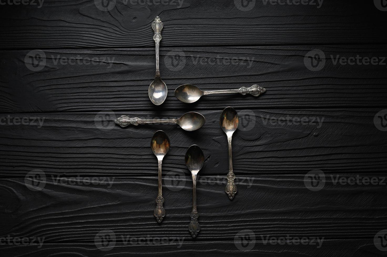 Directly above a shot of old spoons on a black table photo
