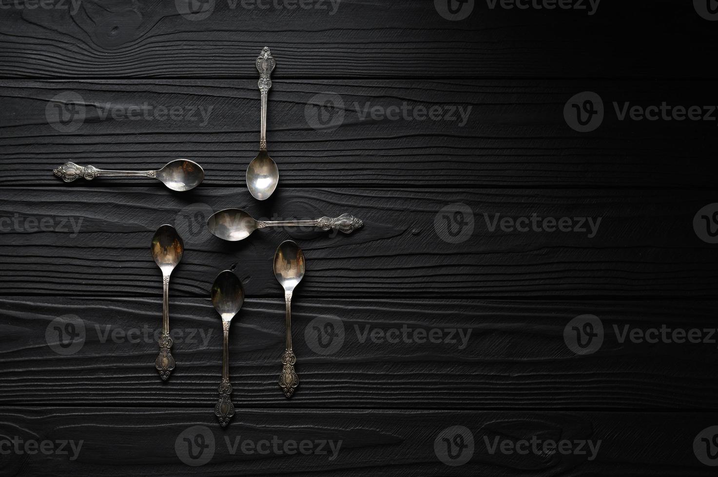 Directly above a shot of old spoons on a black table photo