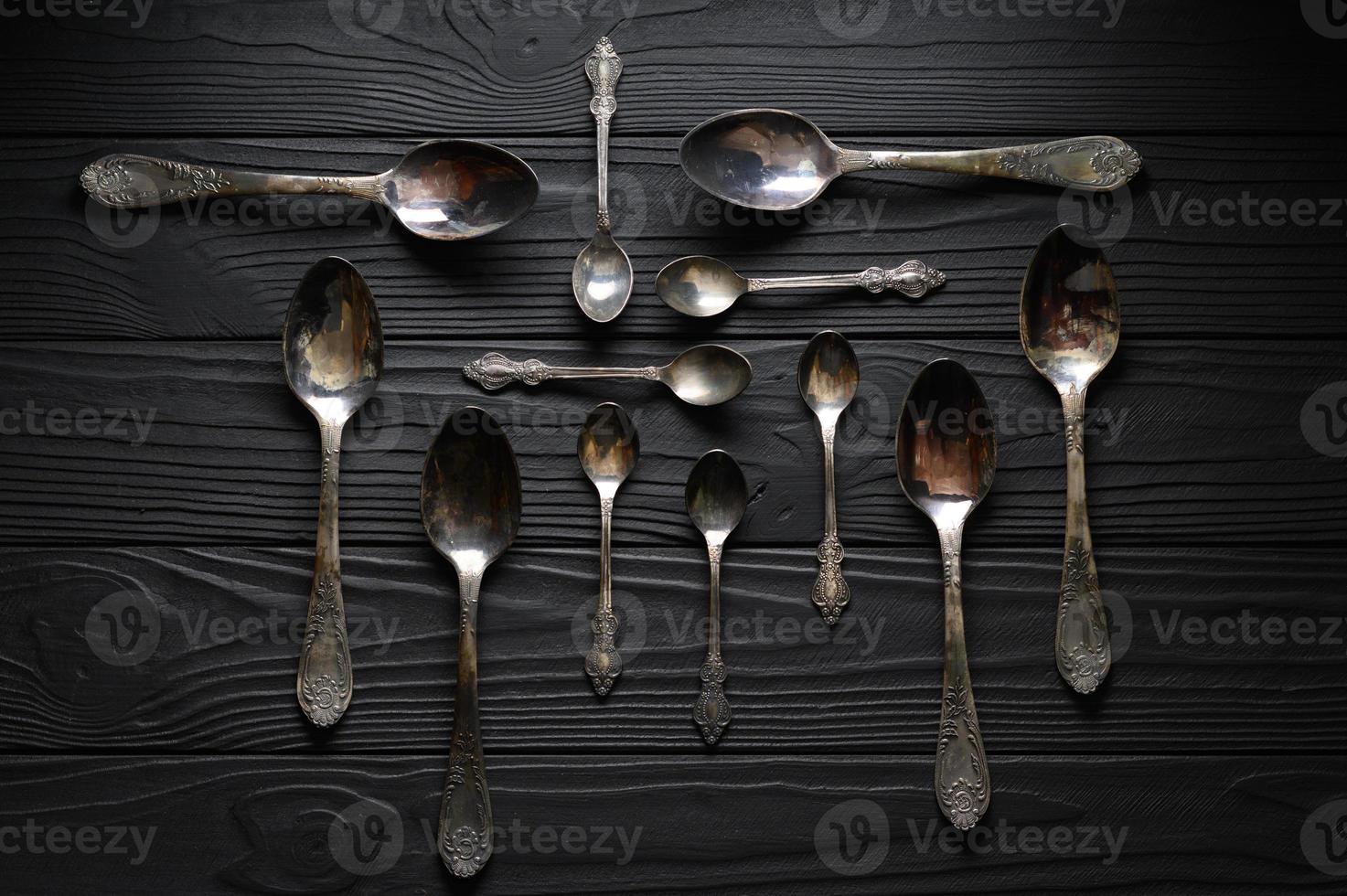 Directly above a shot of old spoons on a black table photo