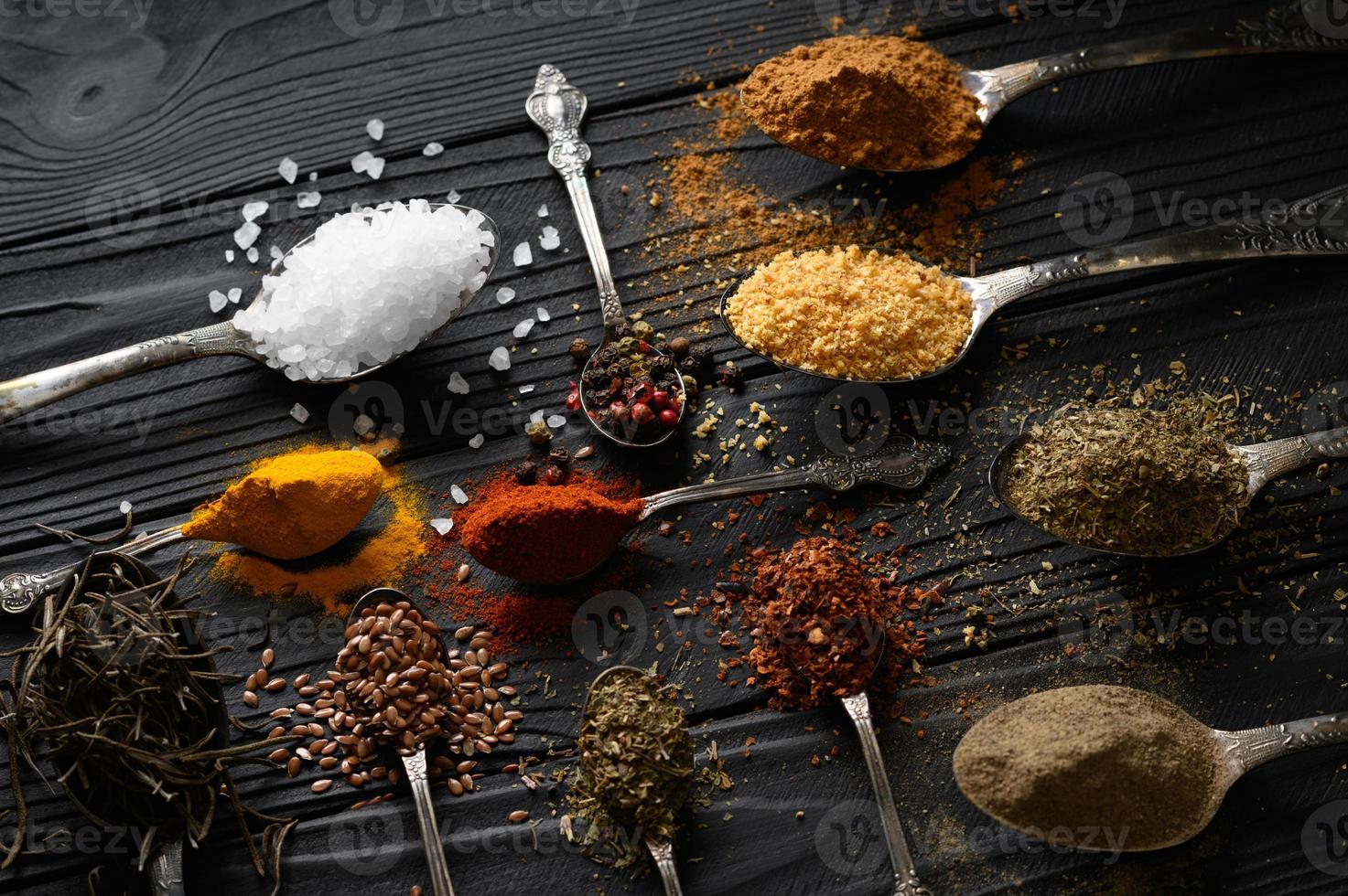 Colorful various herbs and spices for cooking on dark wooden rustic background photo