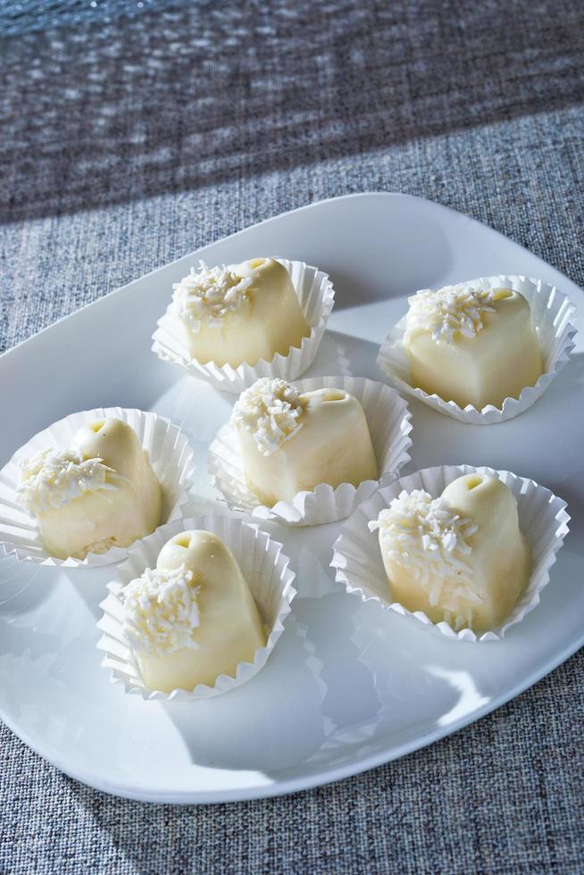 Chocolates in heart shaped white chocolate on the tablecloth photo