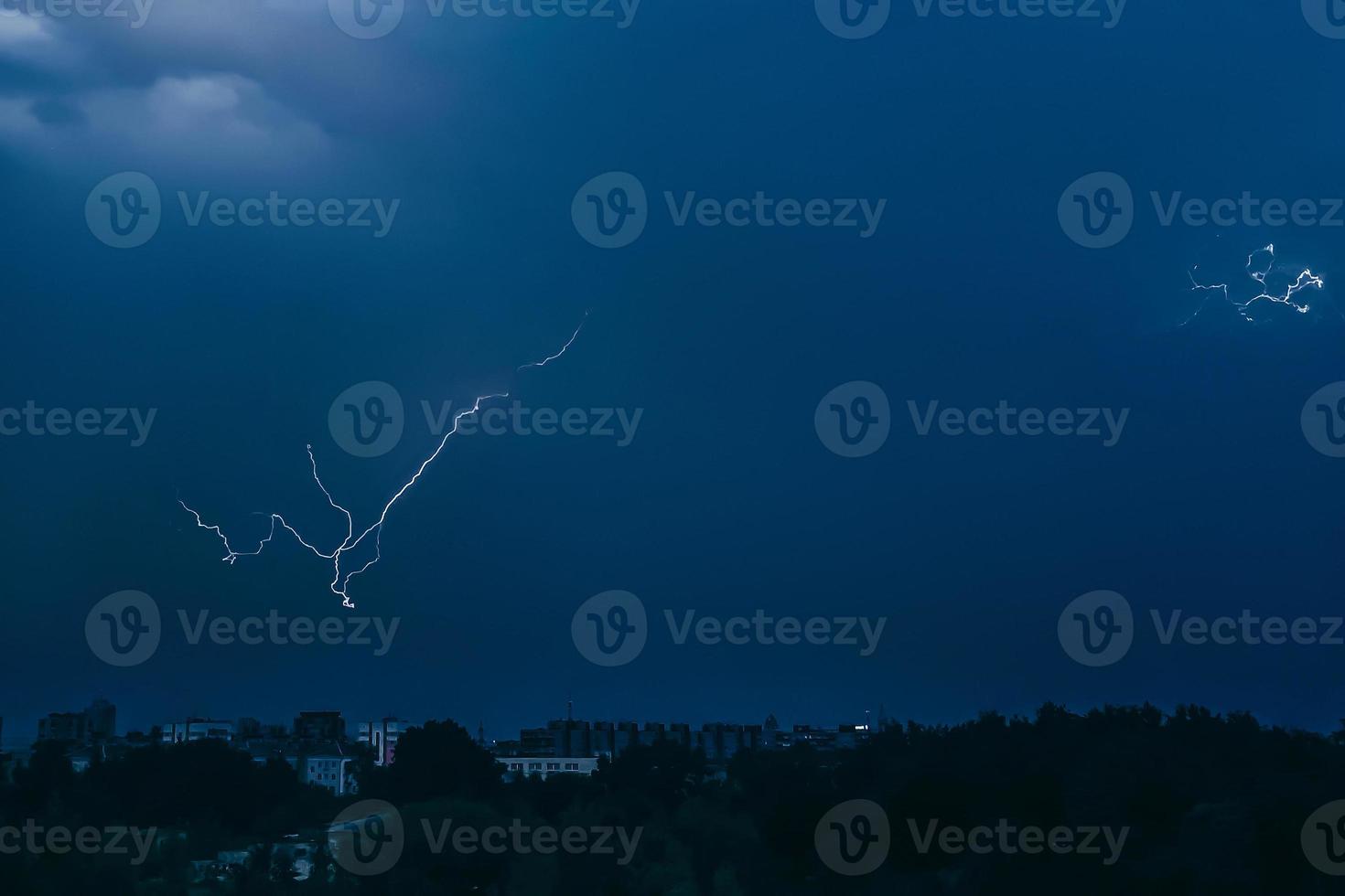 relámpago en el cielo sobre la ciudad. destellos brillantes en la noche oscura. nubes de tormenta y descargas eléctricas en la atmósfera. foto