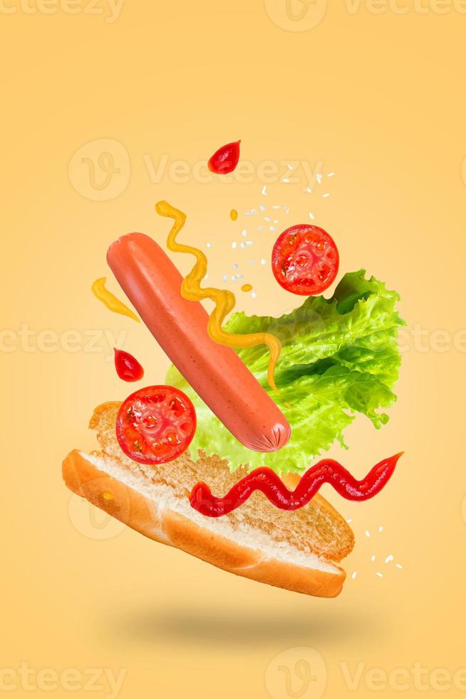 Levitating hot dog on yellow background. Flying hotdog ingredients. photo