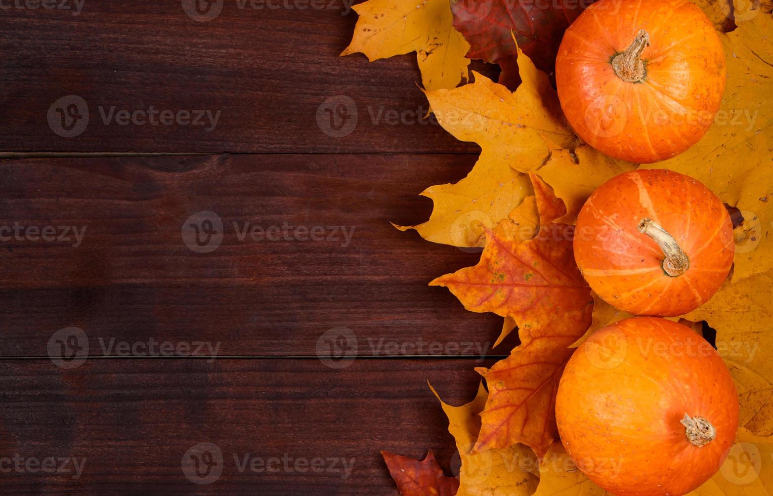 Autumn background. Ripe pumpkins and yellow fallen leaves. Harvest and Thanksgiving concept. Halloween celebrations. photo