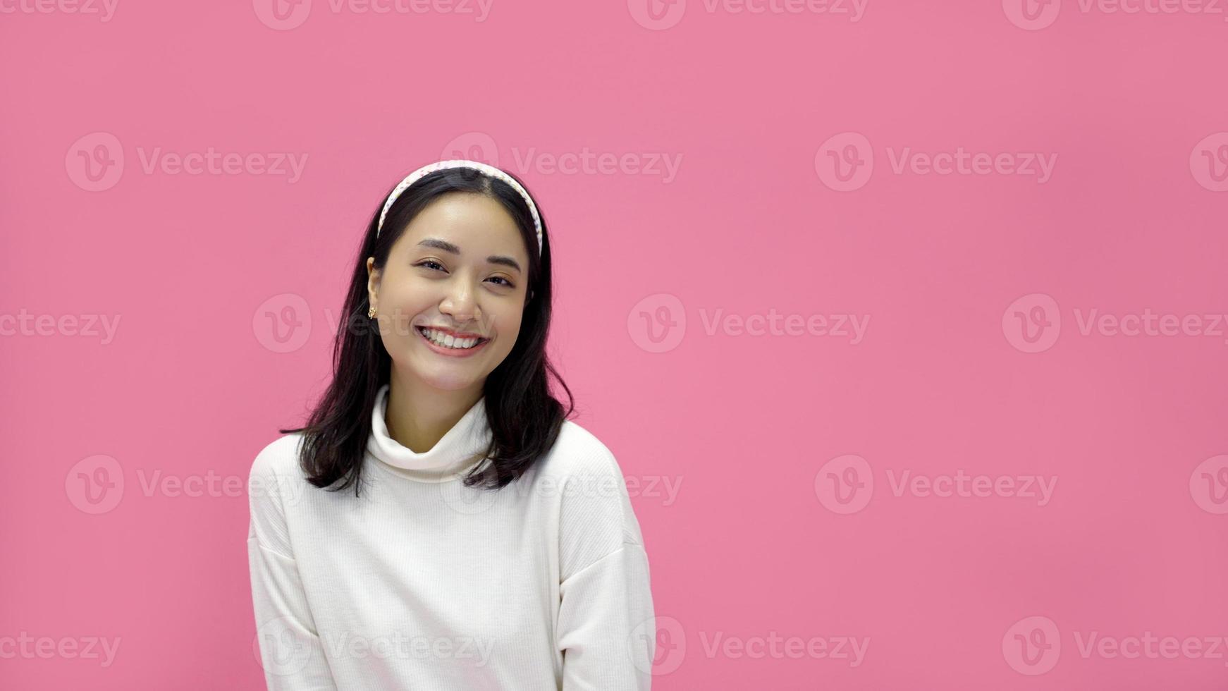 happy young woman Asian smiling and having good time, laughing, looking to side on pink background photo