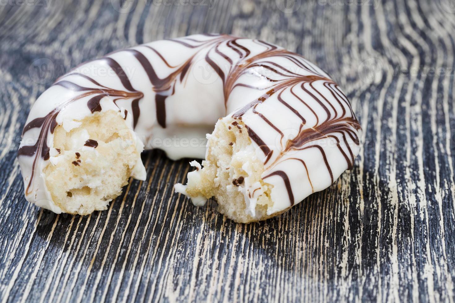 a fresh doughnut covered with white chocolate , closeup photo