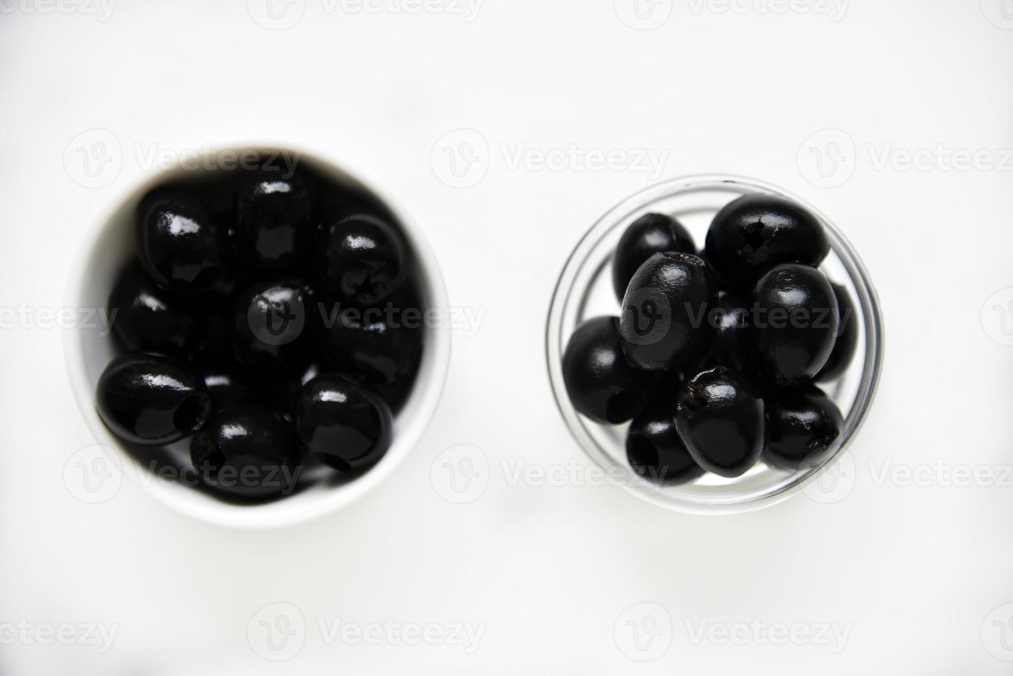 Black olives in a white and glass saucepan on a white background. photo