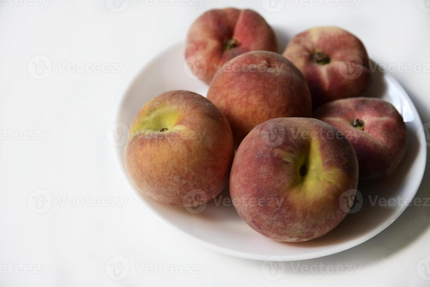 jugosos melocotones rojos y amarillos en un plato blanco. deliciosos melocotones para el almuerzo. foto