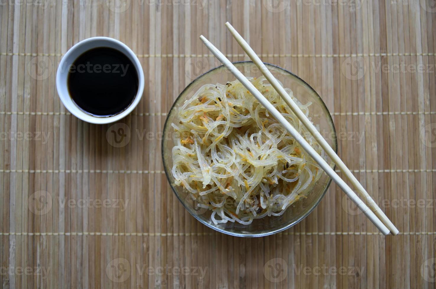 Korean rice noodles with meat and spices in a glass bowl. Delicious noodles with meat and spices. Korean noodle sticks. photo