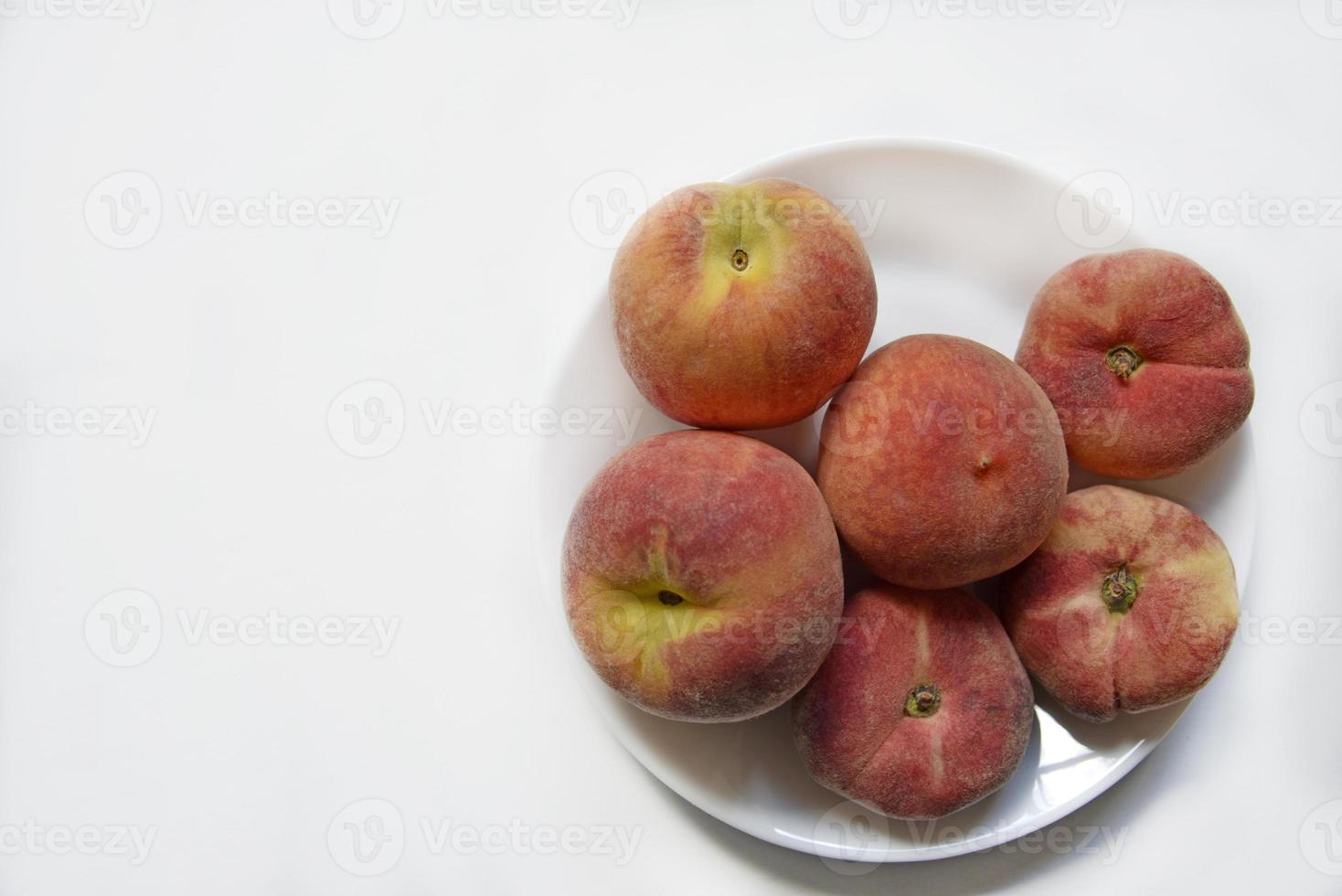 jugosos melocotones rojos y amarillos en un plato blanco. deliciosos melocotones para el almuerzo. foto