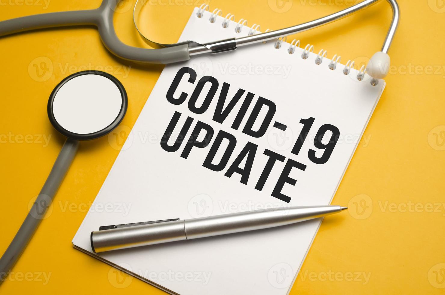 covid 19 update written in notebook on orange table photo