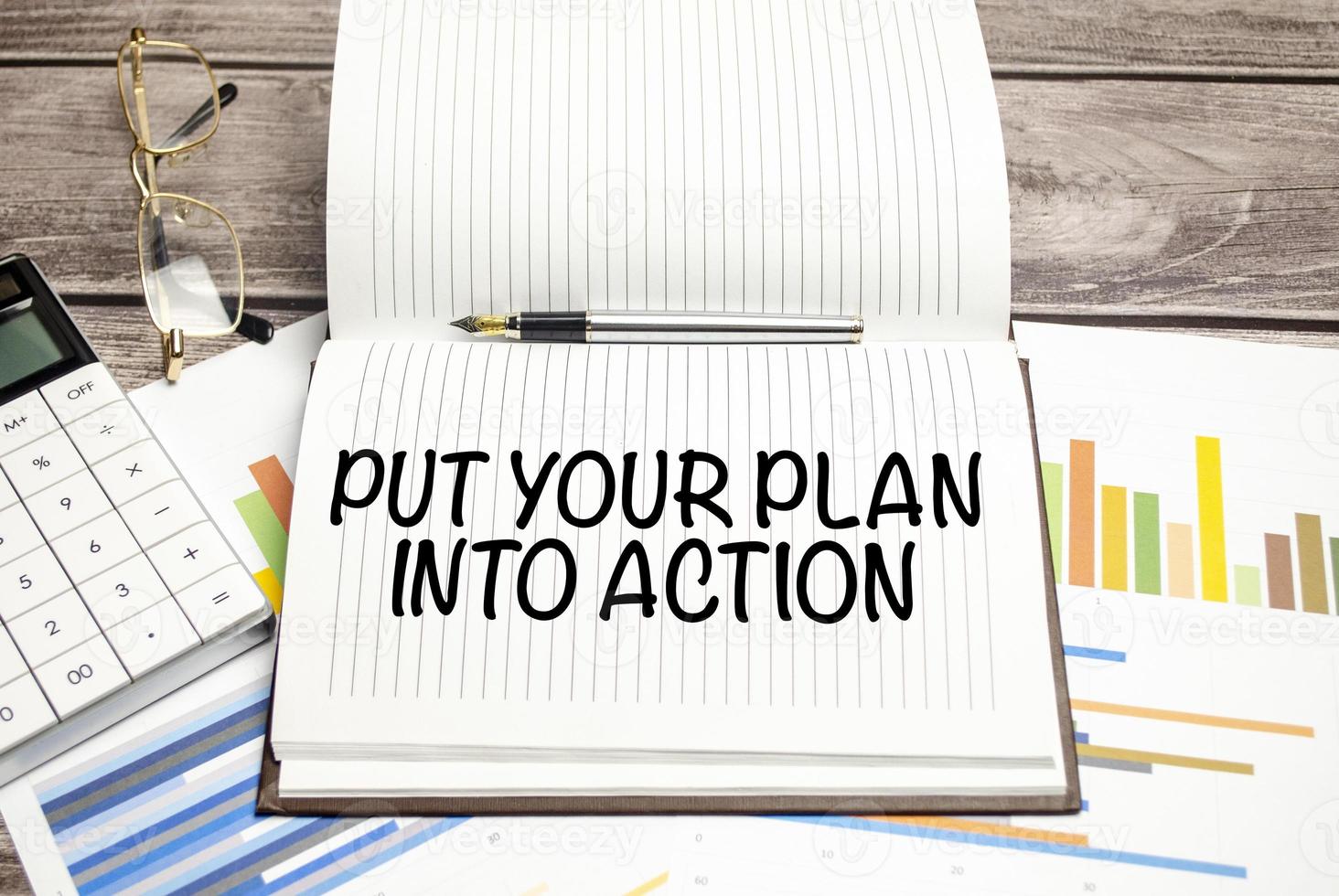 PUT YOUR PLAN INTO ACTION word on the paper notebook. photo