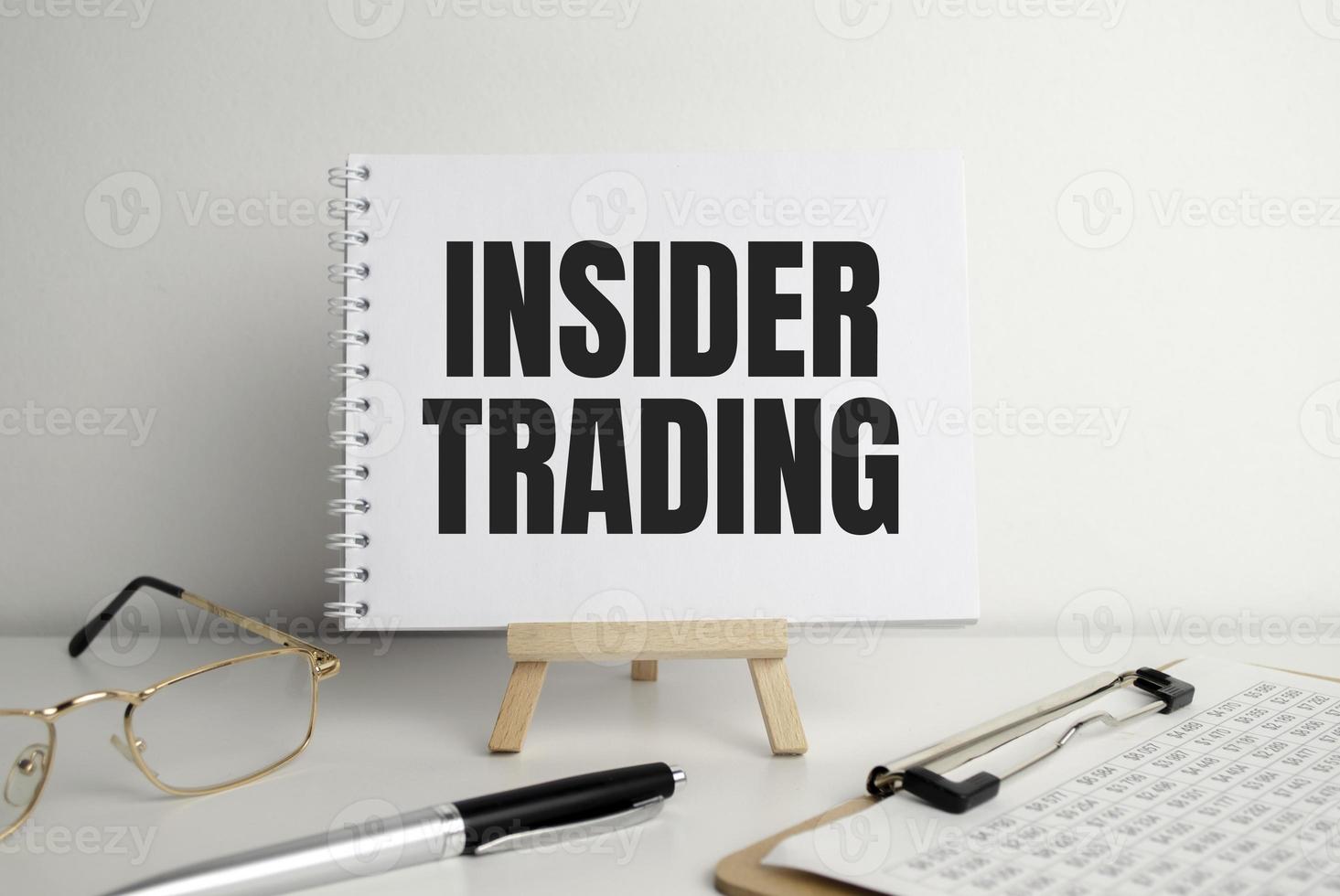 Text INSIDER TRADING on white paper on clipboard with chart and calculator photo