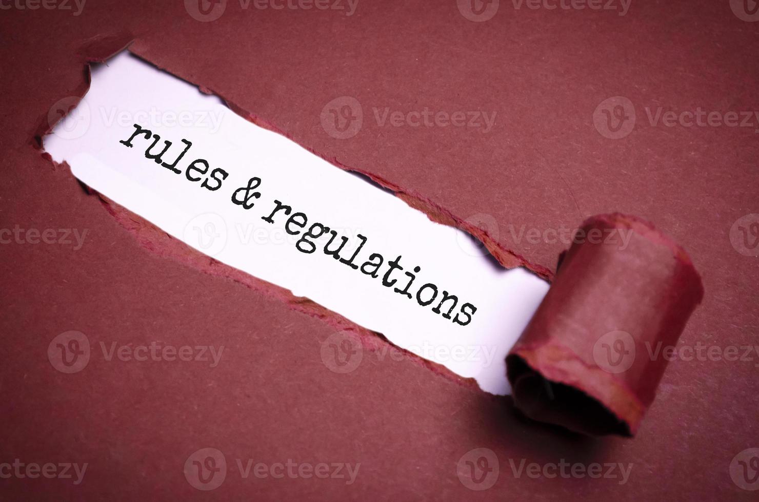 palabra de reglas y regulaciones bajo papel rojo rasgado foto